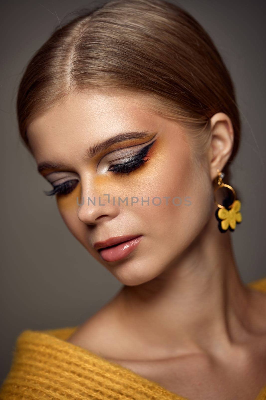 Beauty blonde model girl with fashionable creative make-up, bright eye line. Creative yellow eye makeup ideas.