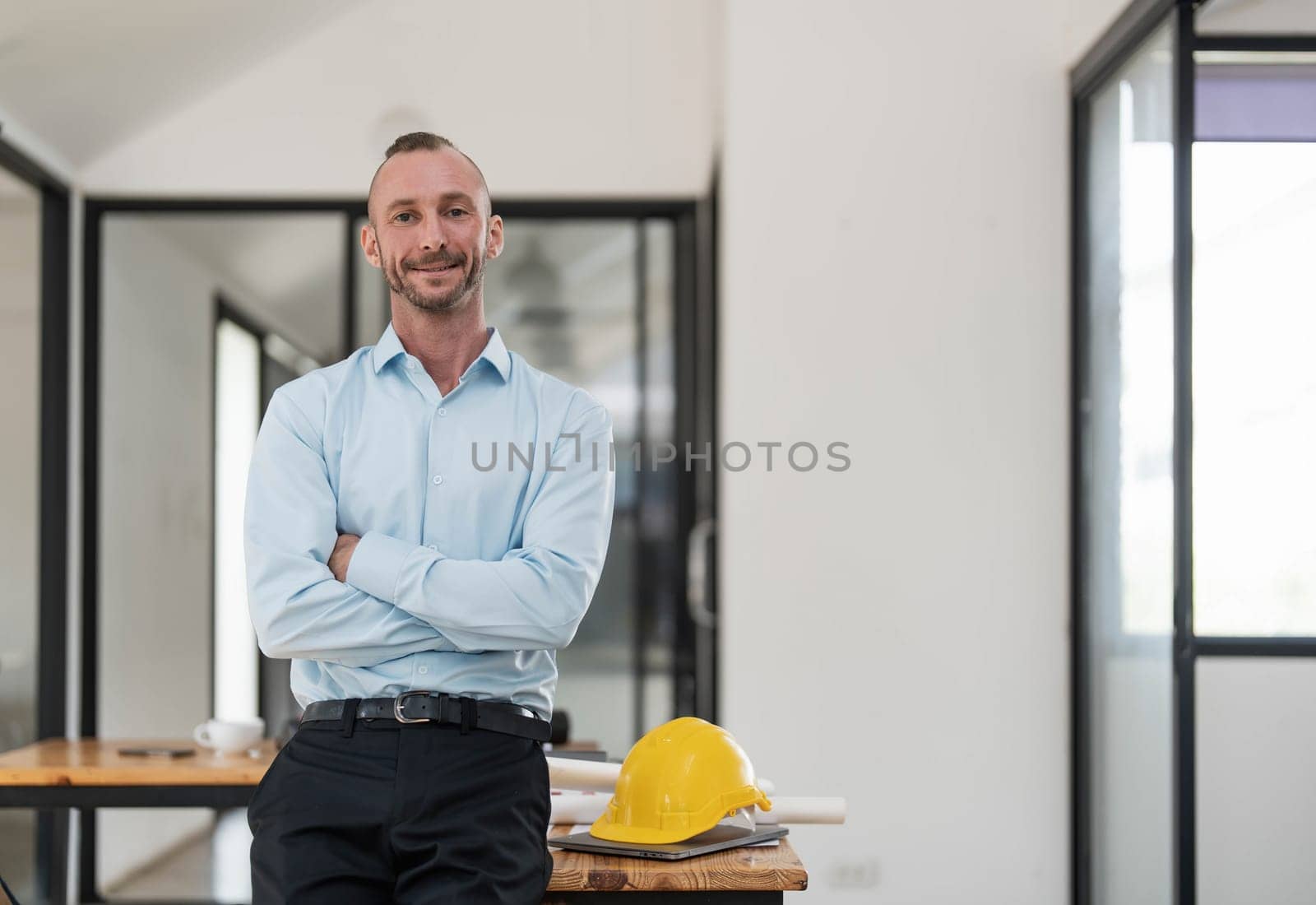 Portrait, Successful and confident Caucasian male engineer or architect stands with arms crossed in the engineer's office. by wichayada