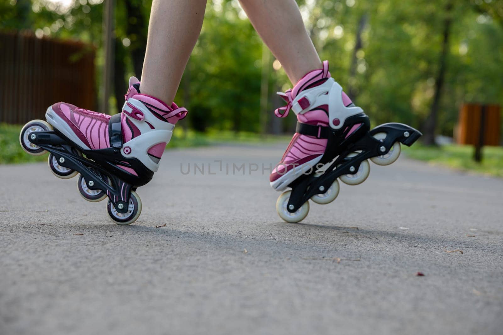 A woman rollerblading on an asphalt alley. A city park suitable for sports. Playing sports outdoors. Active relaxation in nature.
