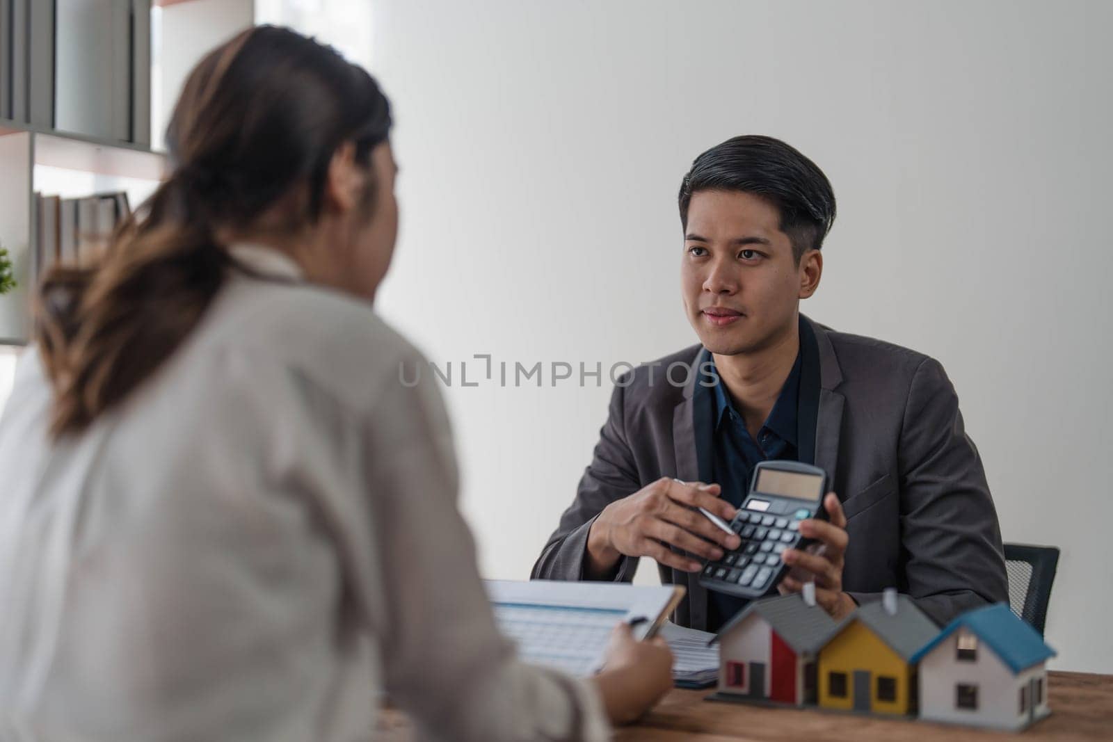 Sealing a deal. Asian people business real estate agent with client consulting and discussing at office desk. talking with contract agreement before signing. by wichayada