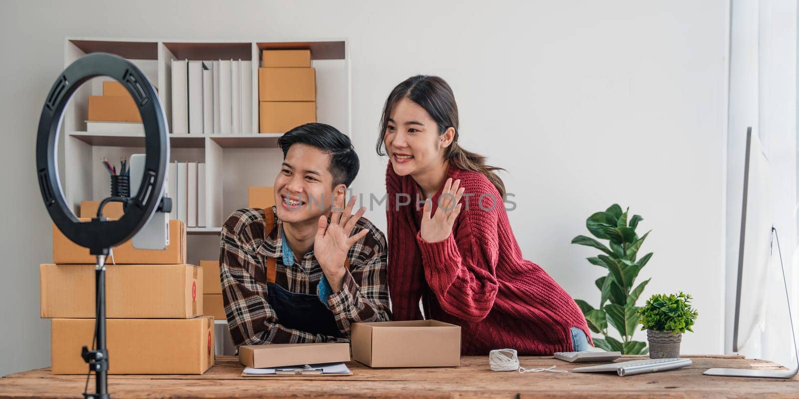 Young asian people couple Male and female small business owner checking online orders and packing the product together. by wichayada