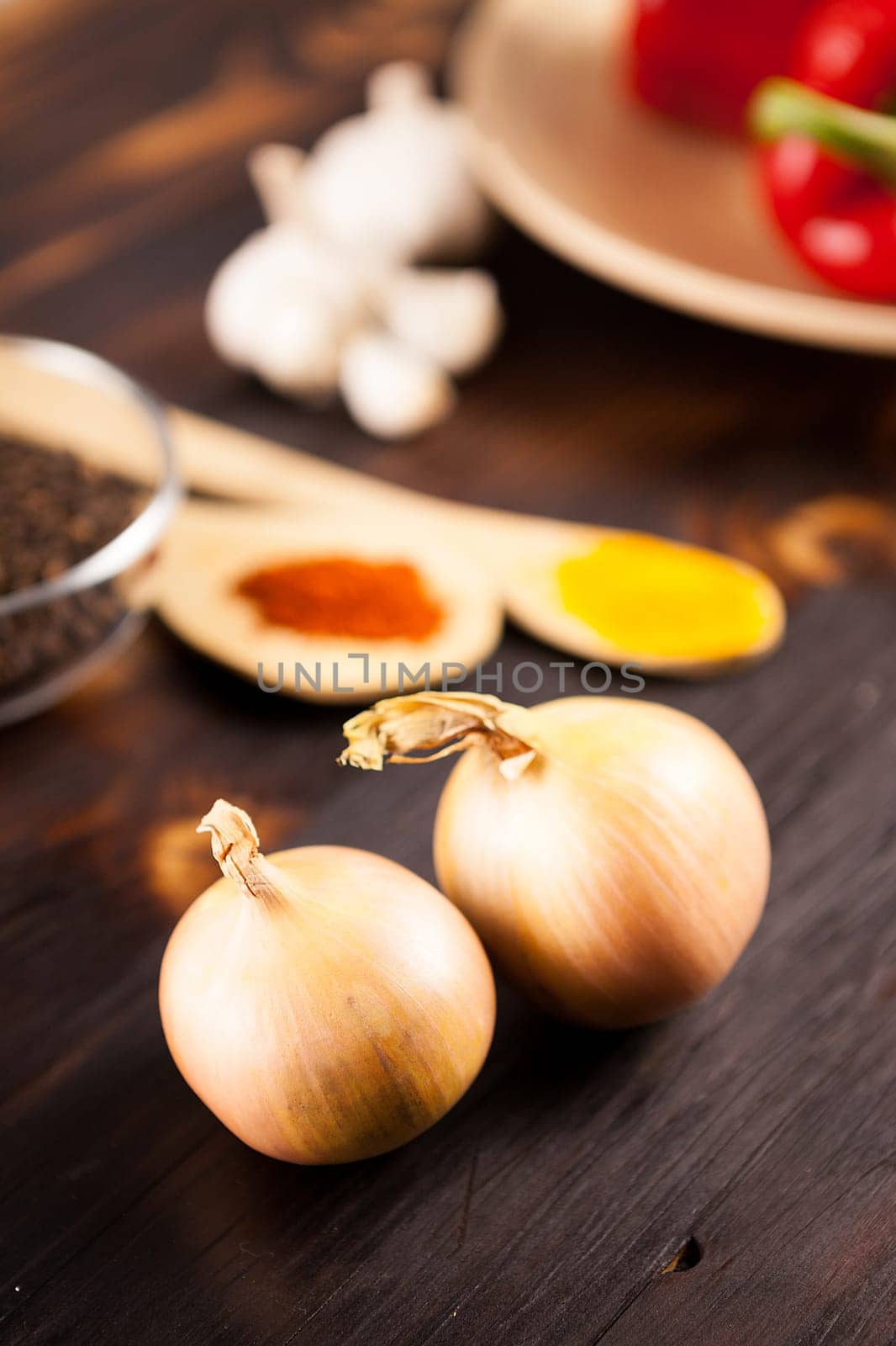 Top close up view on onions with different vegetables blurred on by DCStudio
