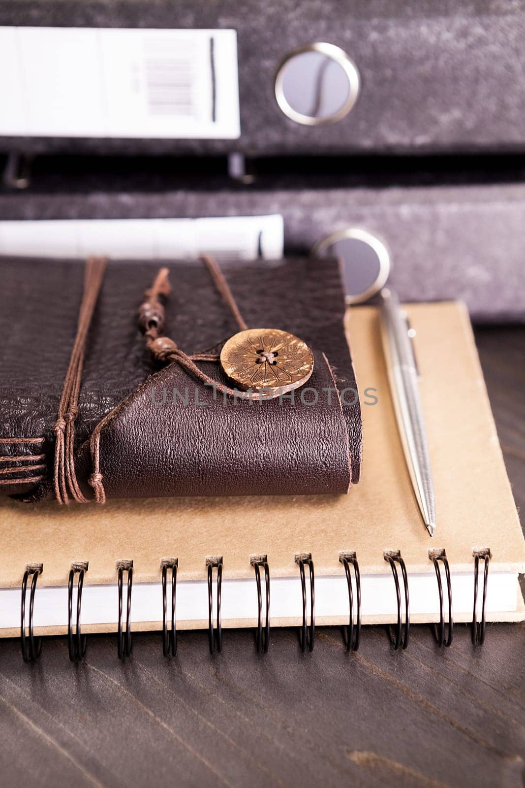 Leather covered vintage retro notebook next to a pile of folders on a table