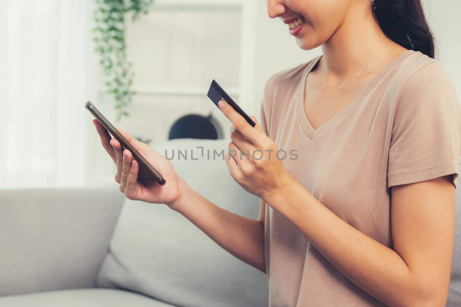 Contented young woman eagerly makes an online purchase using her smartphone. E-commerce business, online purchasing.