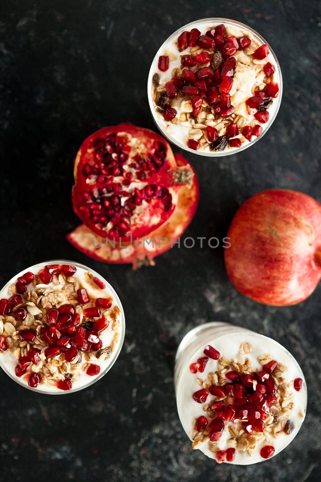 Top view on dessert with yoghurt and pomegranate on dark wooden background
