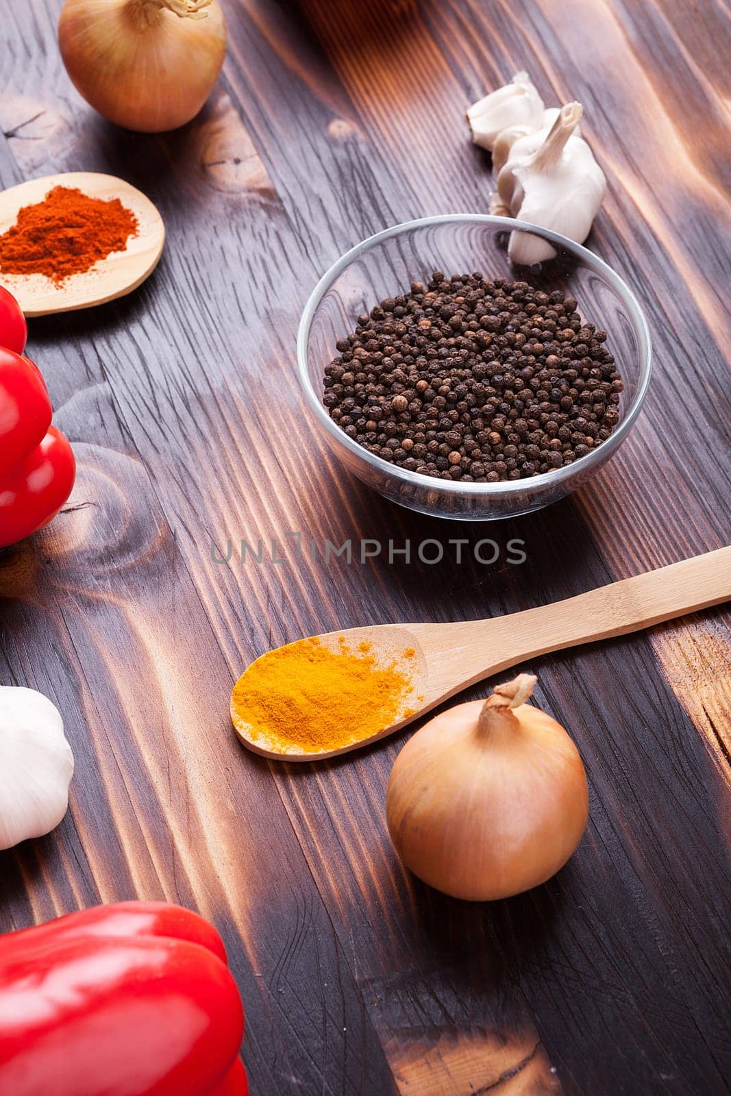 Onions, red sweet pepper and black pepper on burned wooden board