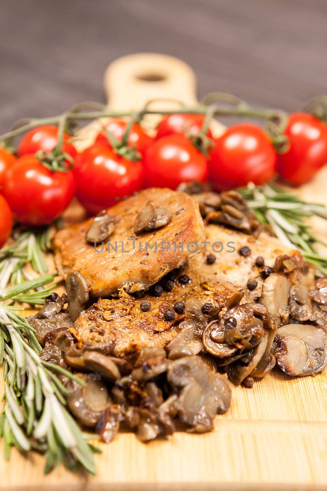 Close up viewon grilled pork and mushrooms next to cherry tomatoes