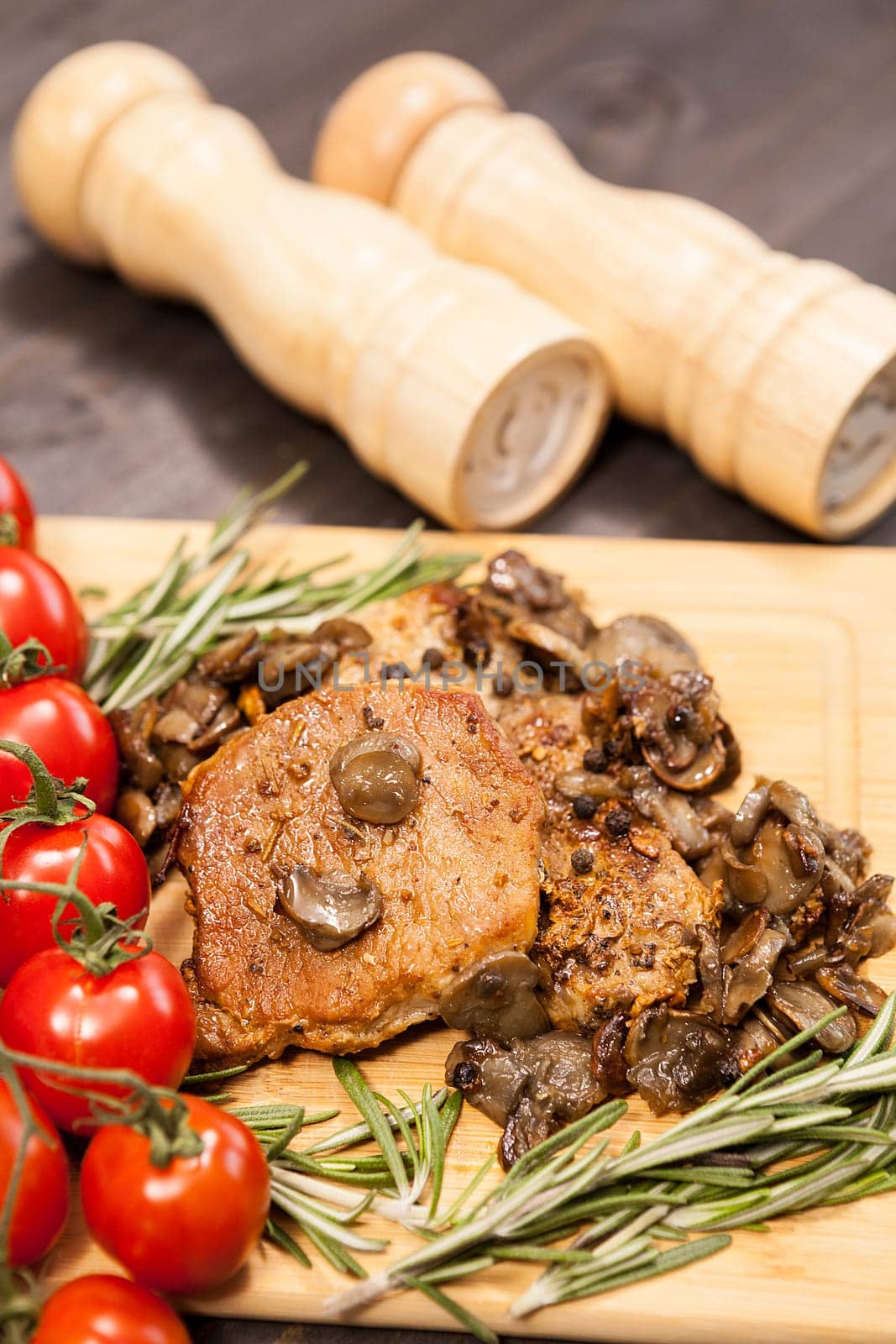 Close up top view on pork steak with grilled mushrooms on wooden board. Delicious healthy food