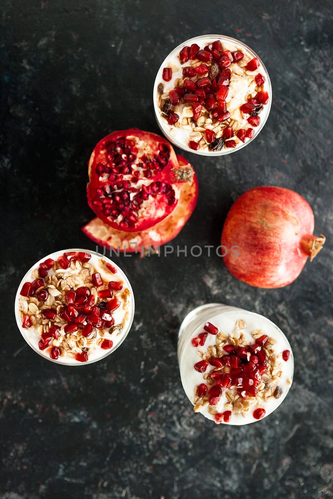 Over top view on healthy and delicious desset made from muesli, yoghurt and pomegranate on dark wooden background