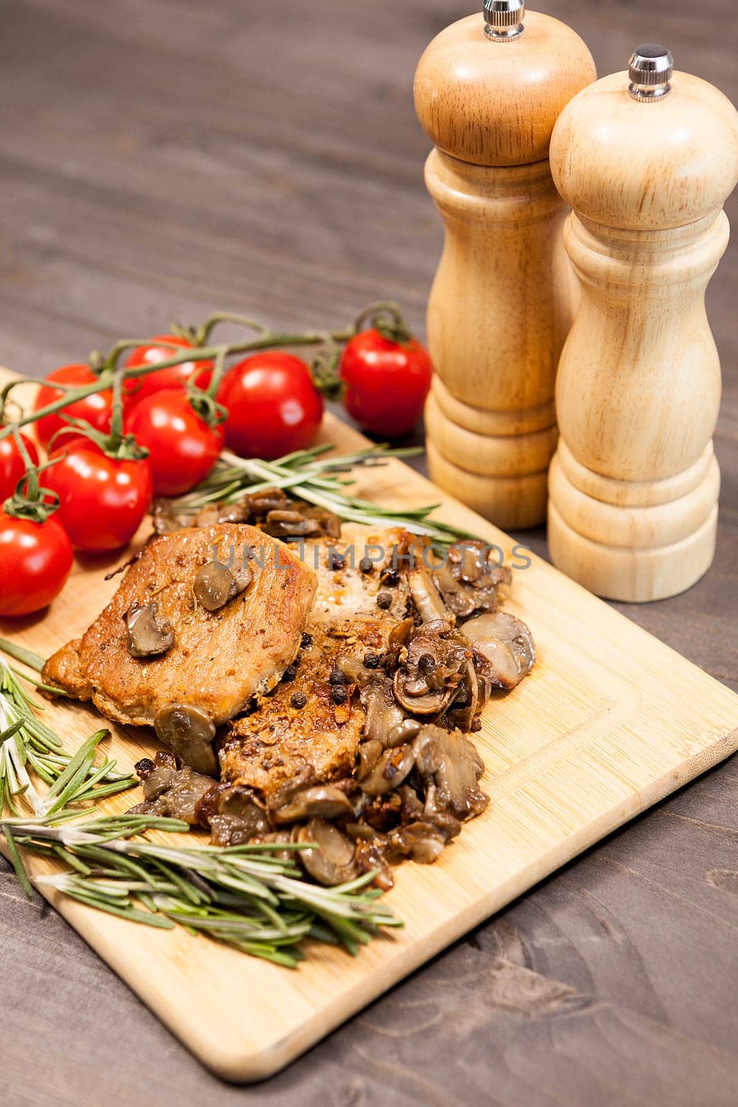 Close up top view on pork steak with grilled mushrooms on wooden board. Delicious healthy food