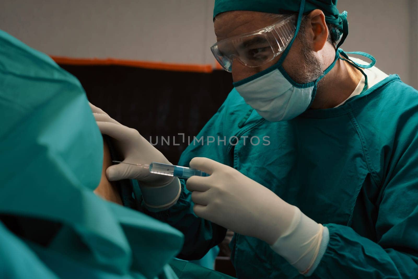 Surgeon inject anesthesia with syringe into the patient before perform surgery in sterile operation room with modern surgical equipments. Medical surgery perform by professional and confident surgeon.