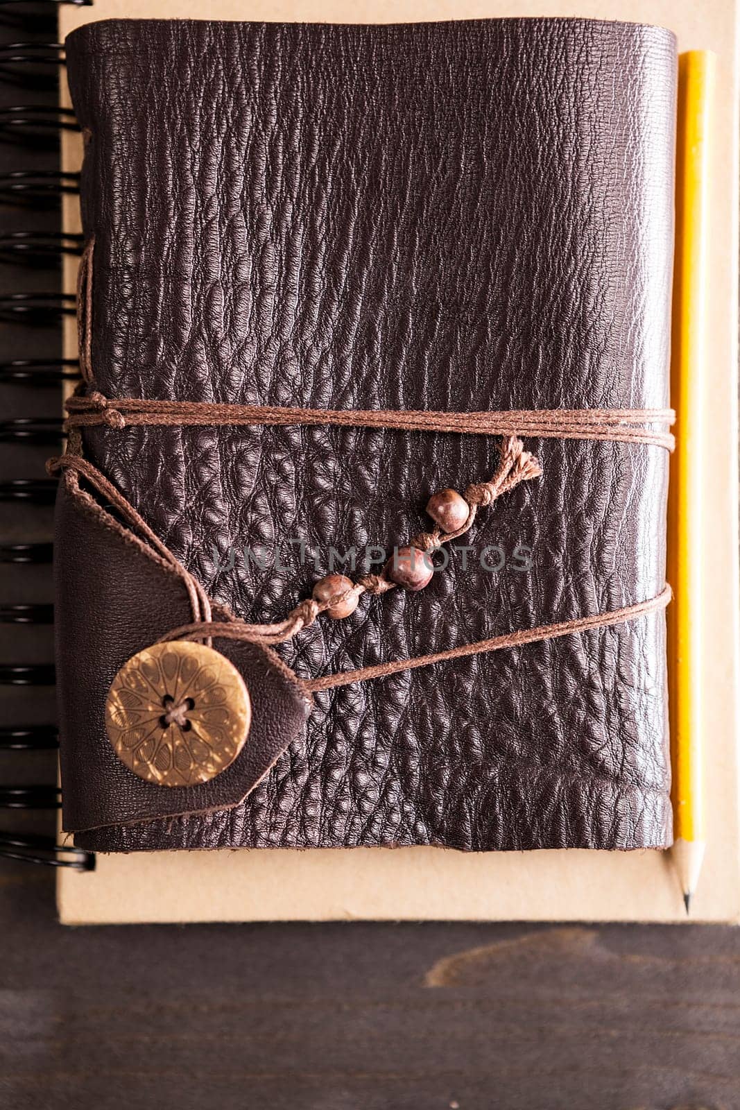 Pencil on retro notebook with leather cover on wooden backgorund
