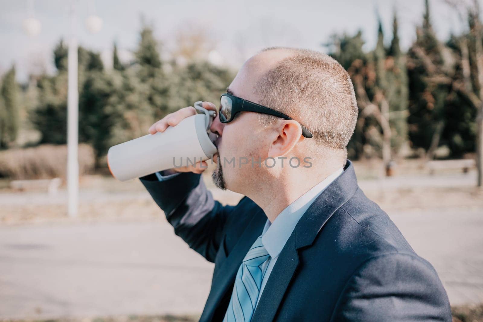 Mature entrepreneur drink coffee in autumn park. Senior executive rest in city park.