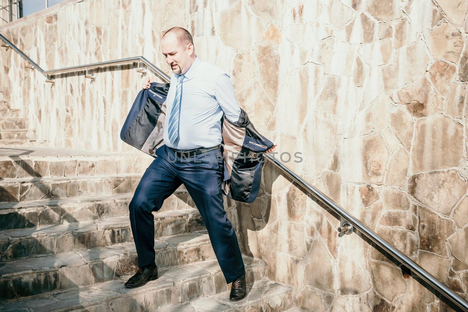 Portrait of a senior professional man in a suit with various problems. A middle-aged businessman with a briefcase descends the stairs.