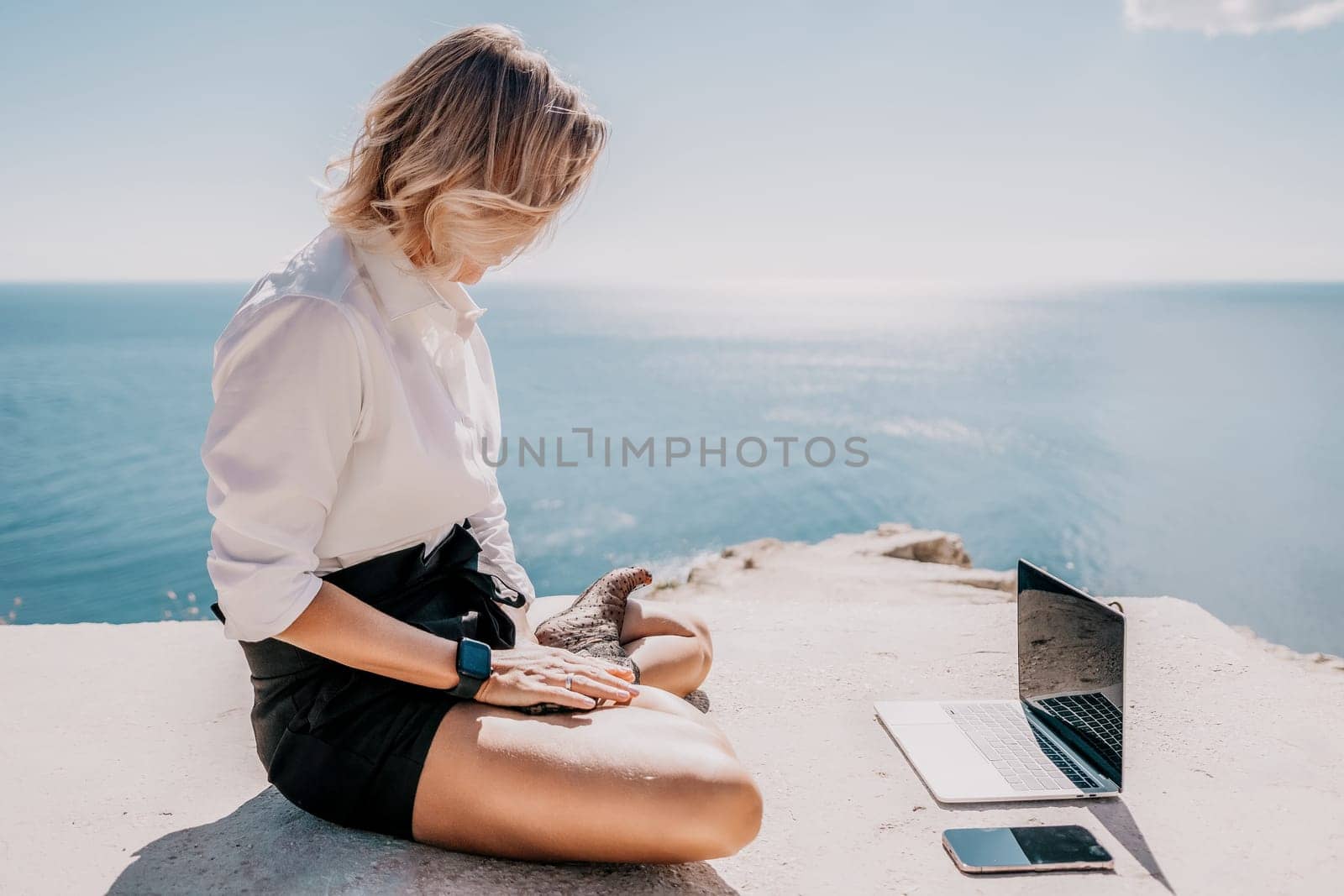 Happy girl doing yoga with laptop working at the beach. beautiful and calm business woman sitting with a laptop in a summer cafe in the lotus position meditating and relaxing. freelance girl remote work beach paradise