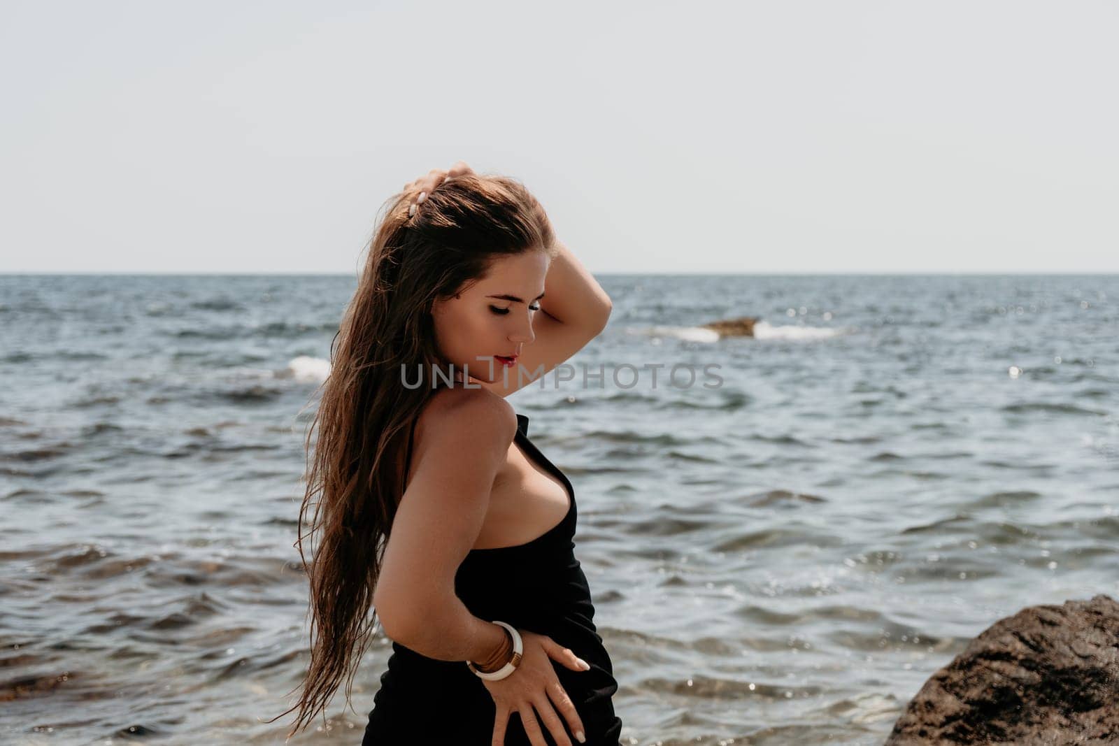 Woman travel sea. Young Happy woman in a long red dress posing on a beach near the sea on background of volcanic rocks, like in Iceland, sharing travel adventure journey