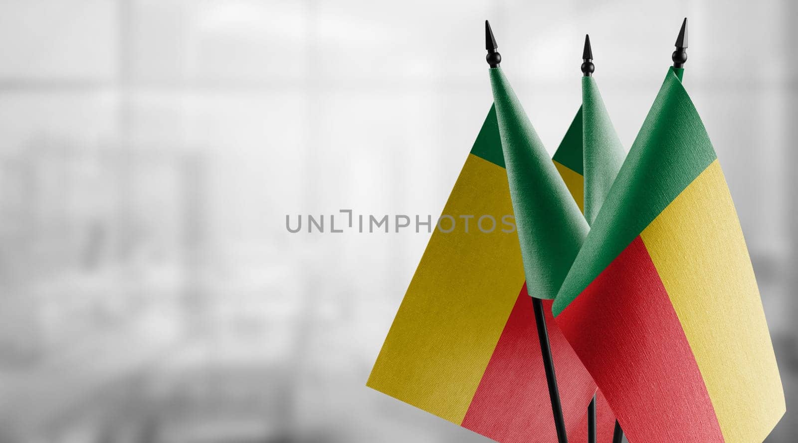 Small flags of the Benin on an abstract blurry background.