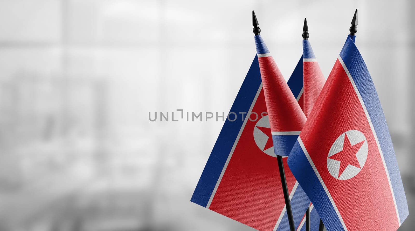 Small flags of the North Korea on an abstract blurry background.