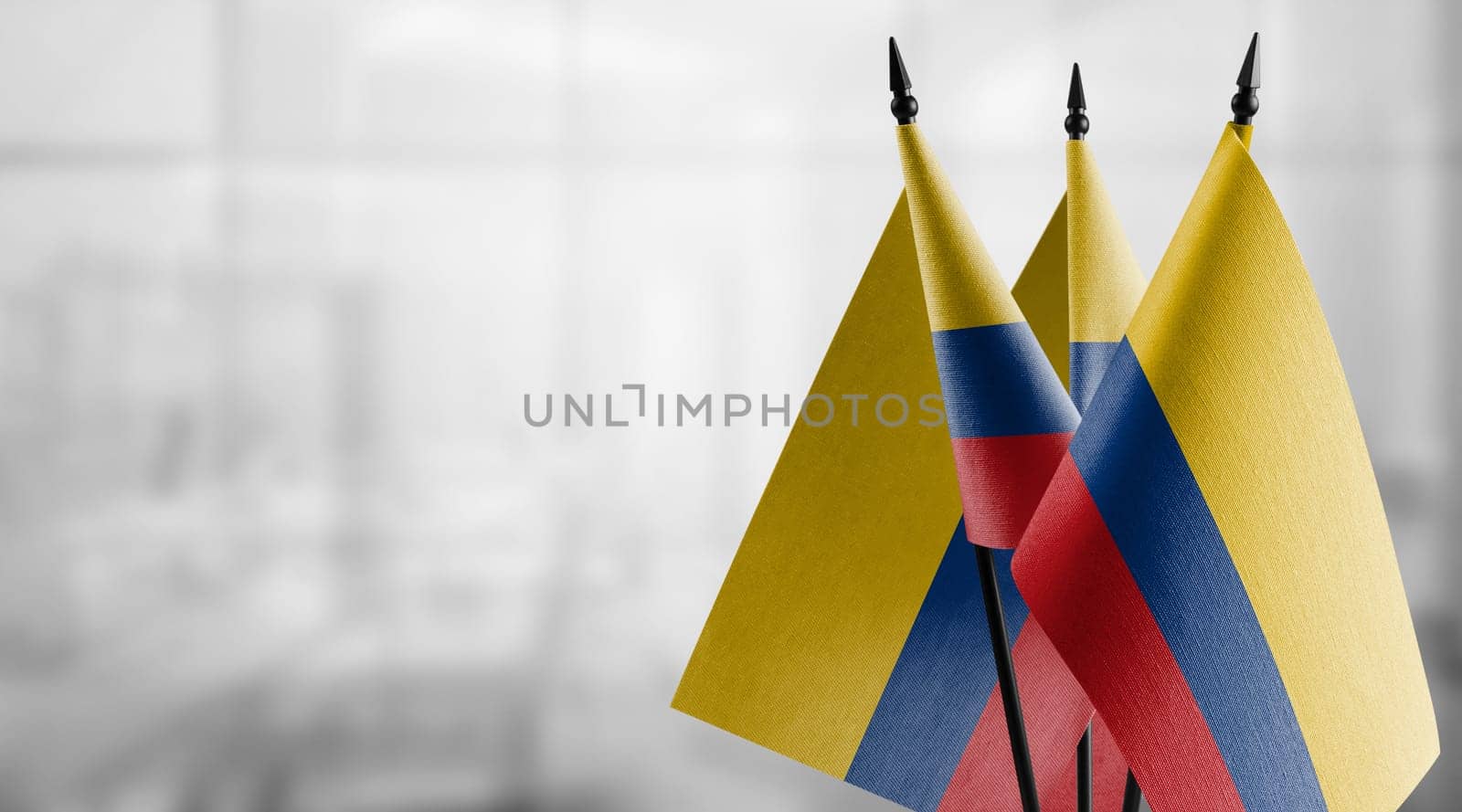 Small flags of the Colombia on an abstract blurry background.
