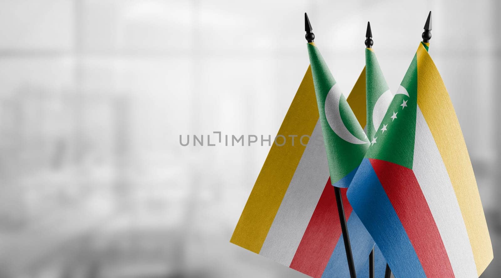 Small flags of the Comoros on an abstract blurry background.