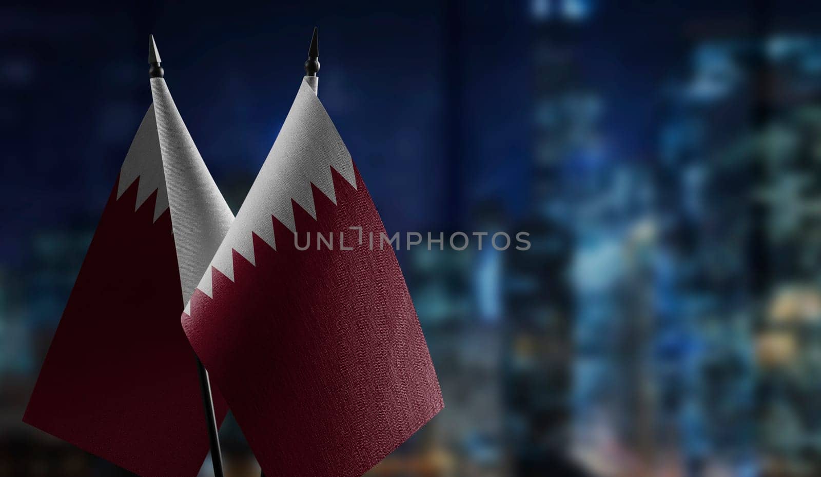 Small flags of the Qatar on an abstract blurry background.