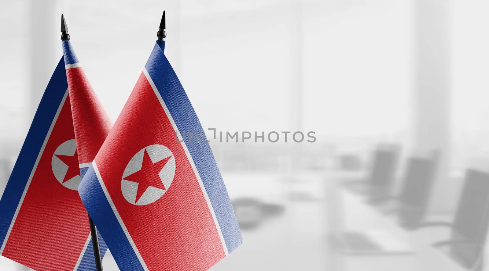 Small flags of the North Korea on an abstract blurry background.