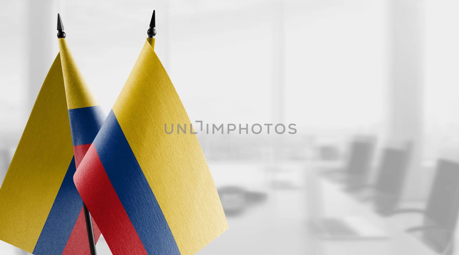 Small flags of the Colombia on an abstract blurry background.