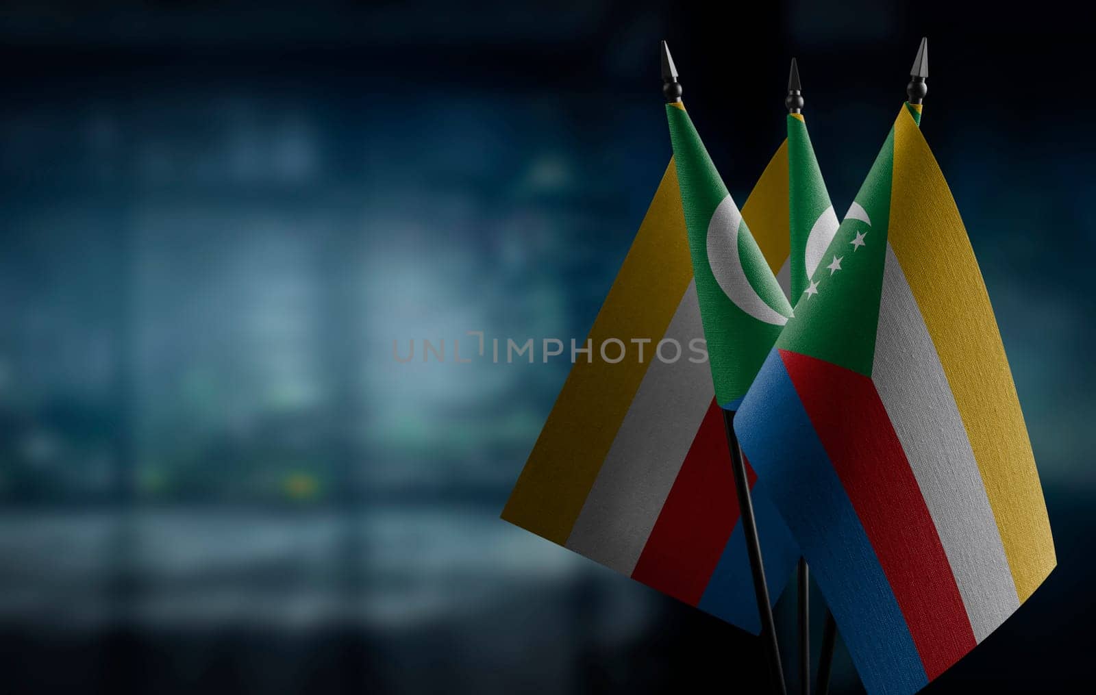 Small flags of the Comoros on an abstract blurry background.