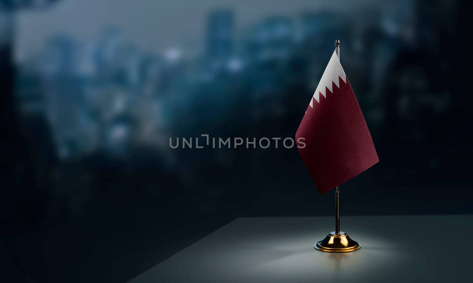 Small flags of the Qatar on an abstract blurry background.