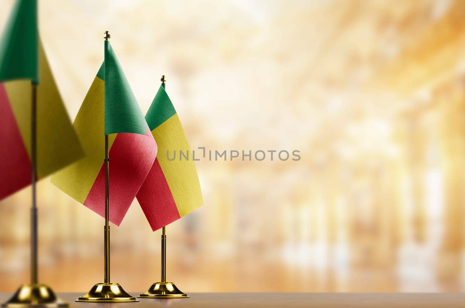 Small flags of the Benin on an abstract blurry background.