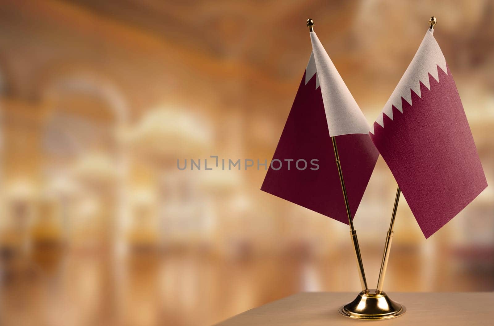 Small flags of the Qatar on an abstract blurry background.
