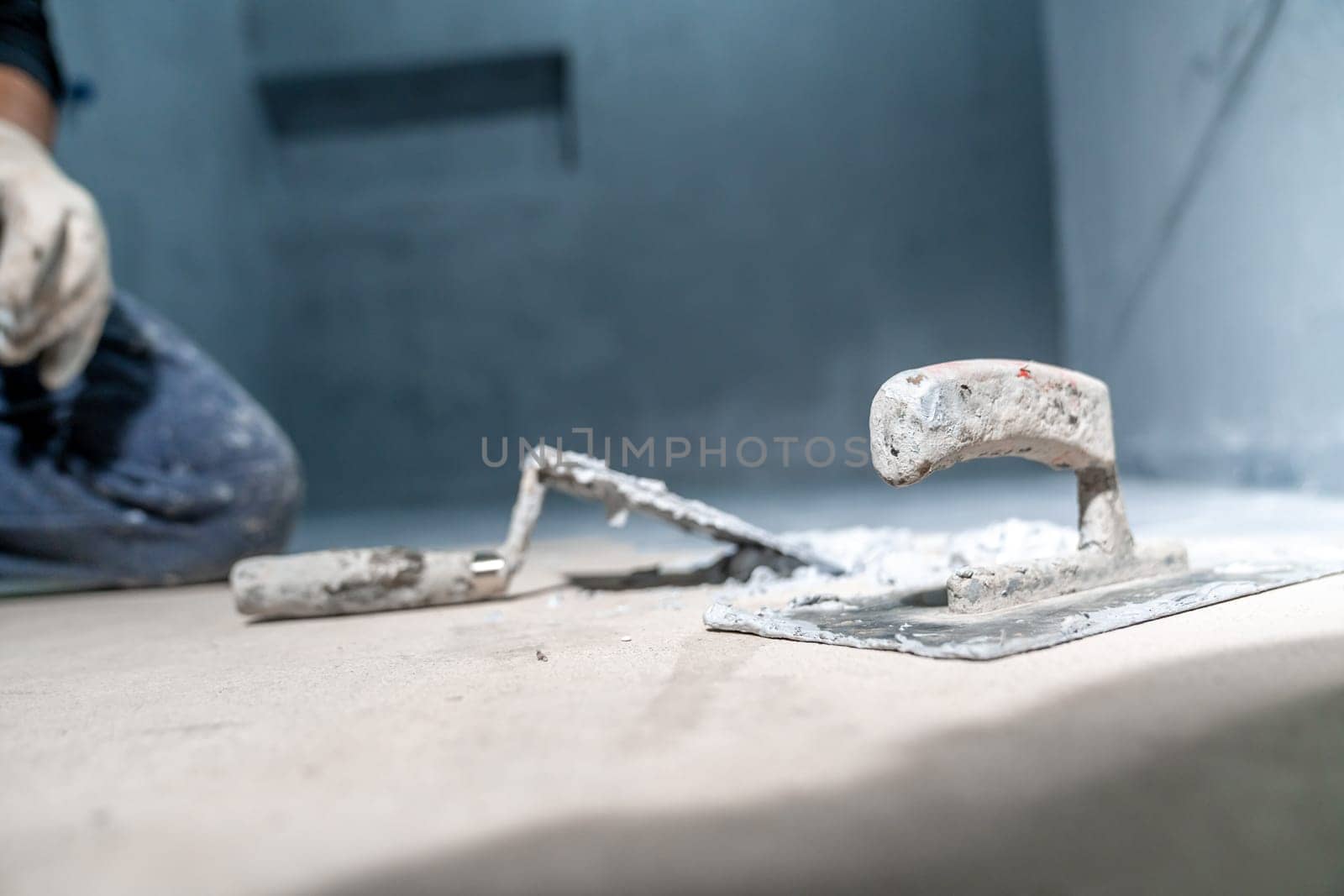work with trowel on floor and wall in new room in building. High quality photo