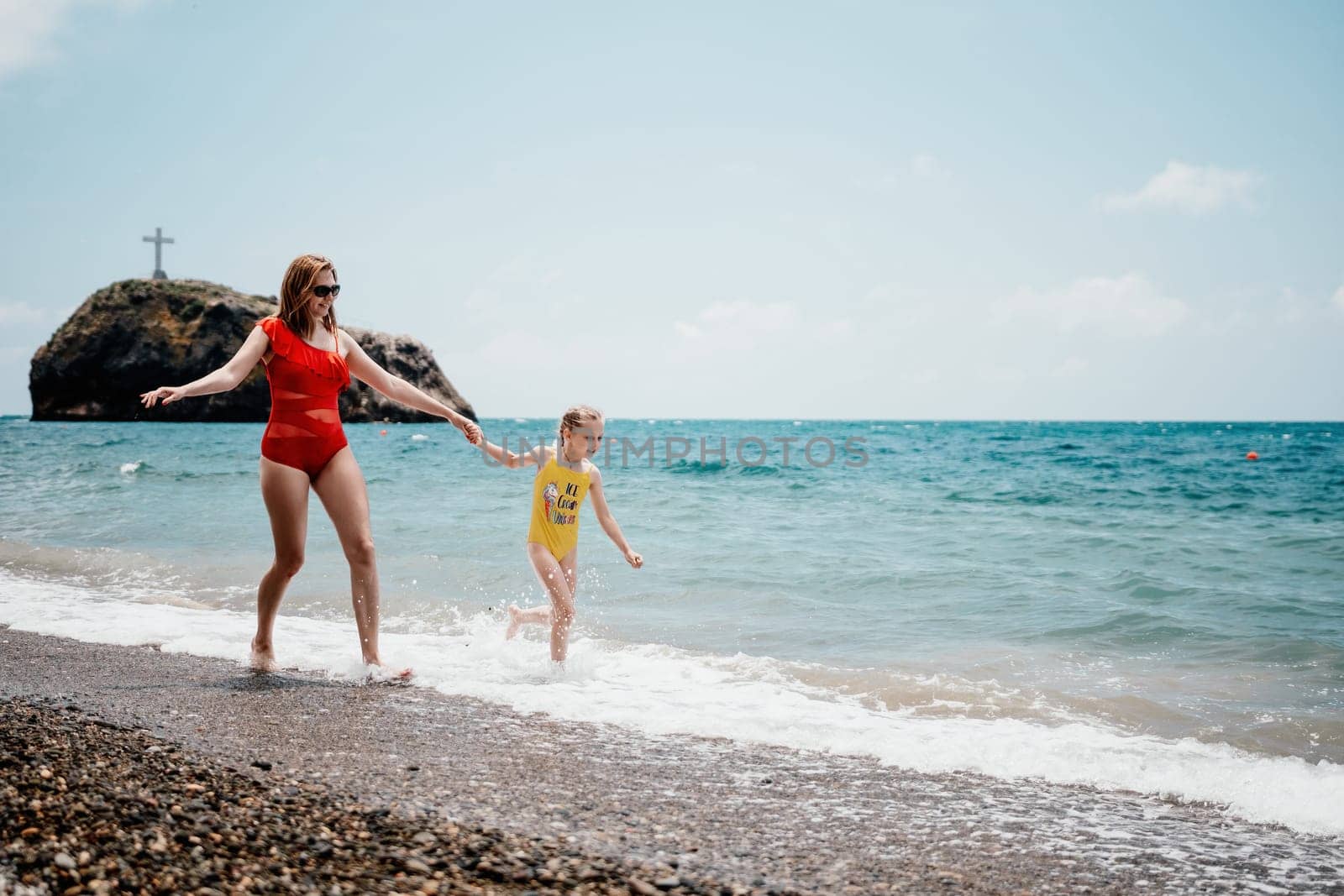Happy loving family mother and daughter having fun together on the beach. Mum playing with her kid in holiday vacation next to the ocean - Family lifestyle and love concept.