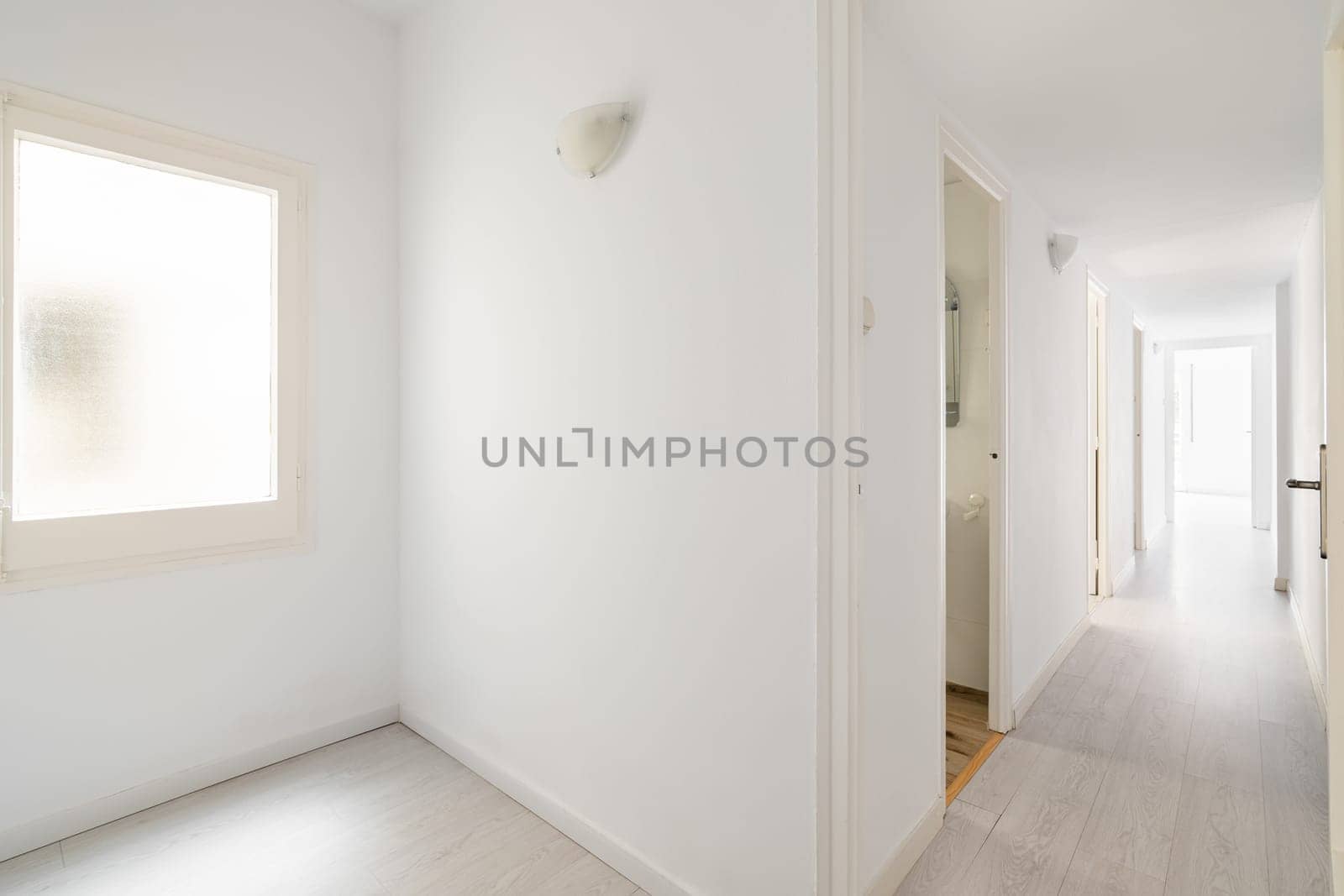 View from the entrance to new empty apartment after renovation in white tones with wooden floor. Cozy apartment in new building with modern minimalist design from the developer by apavlin