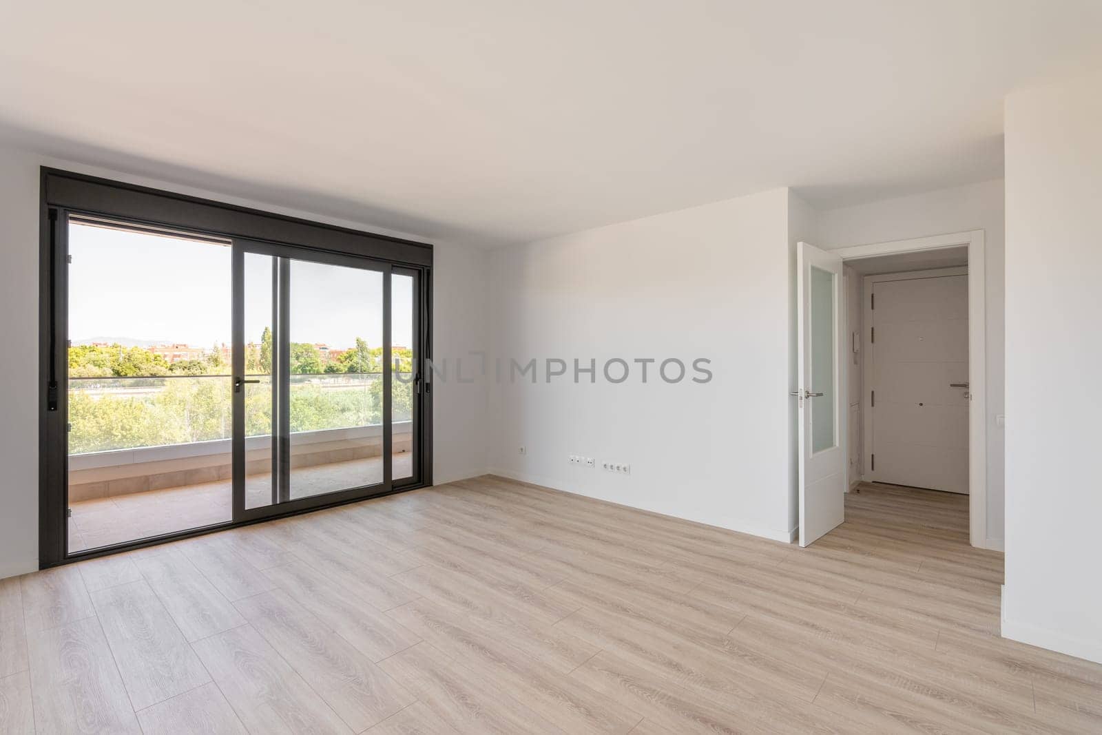 Spacious large room with wooden parquet structure and panoramic window overlooking beautiful landscape among complex of new buildings and balcony with elegant glass border. Mortgage and moving concept by apavlin