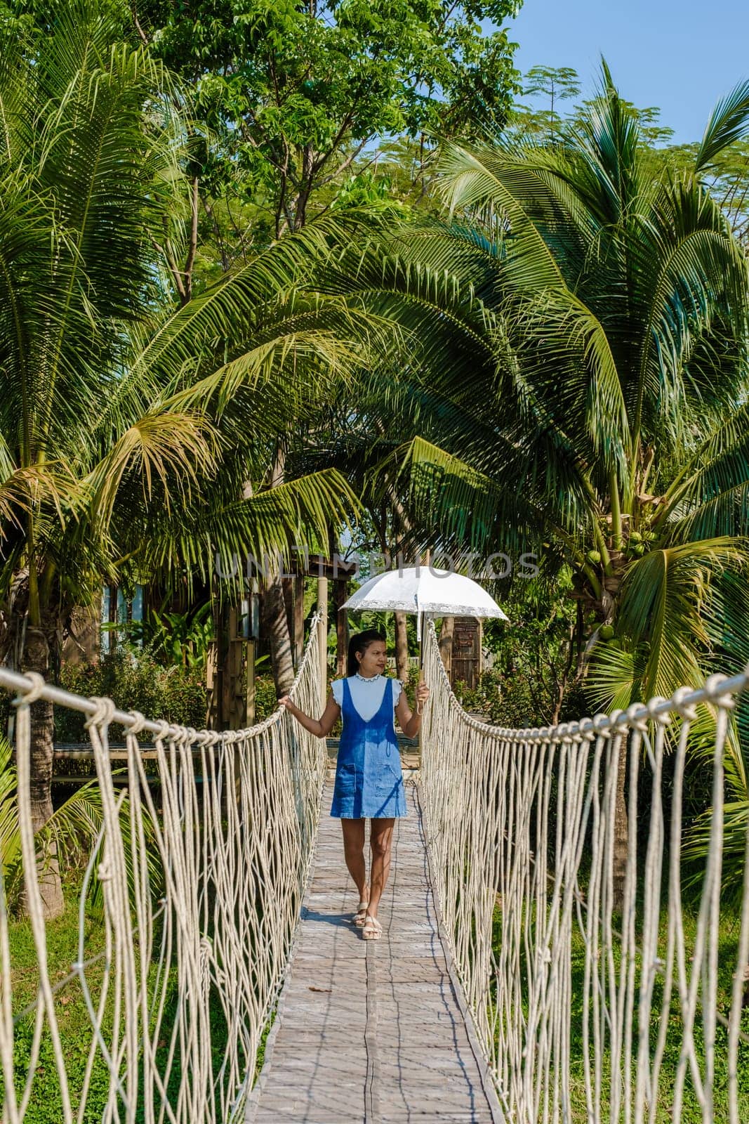 Asian women walking at a wooden bamboo rope bridge in the rainforest of Thailand. bamboo suspension bridge