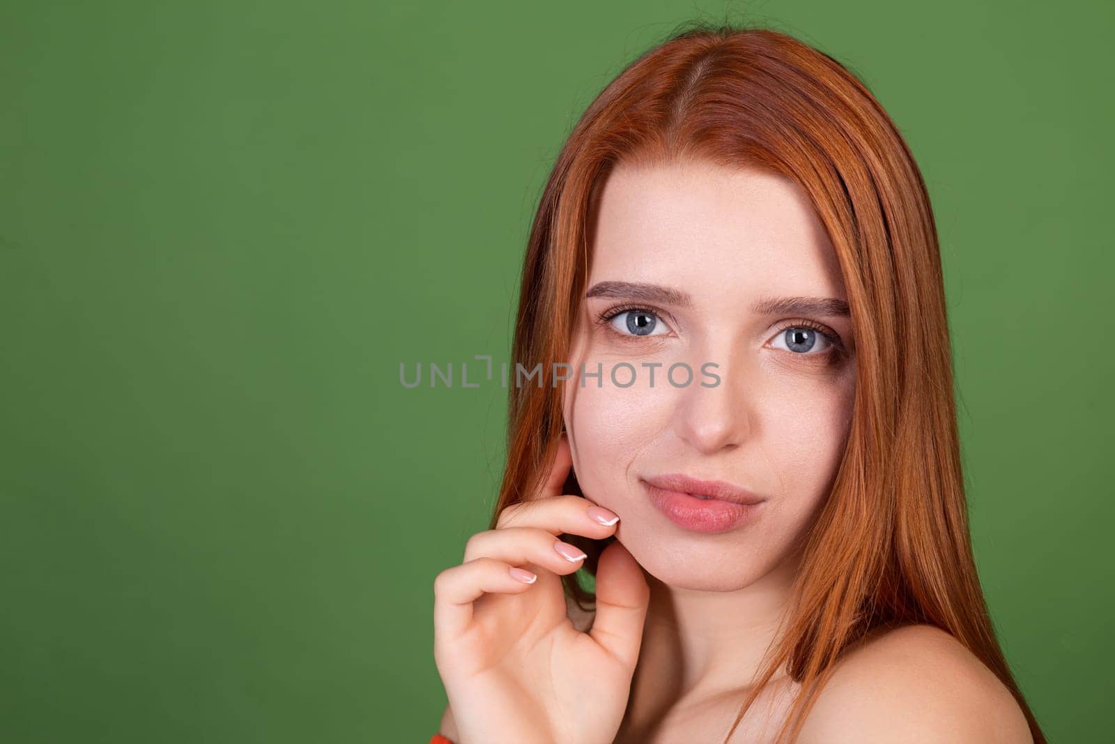 Portrait of pretty red hair young woman with smooth natural soft skin with bare shoulders on green background, beauty concept by kroshka_nastya