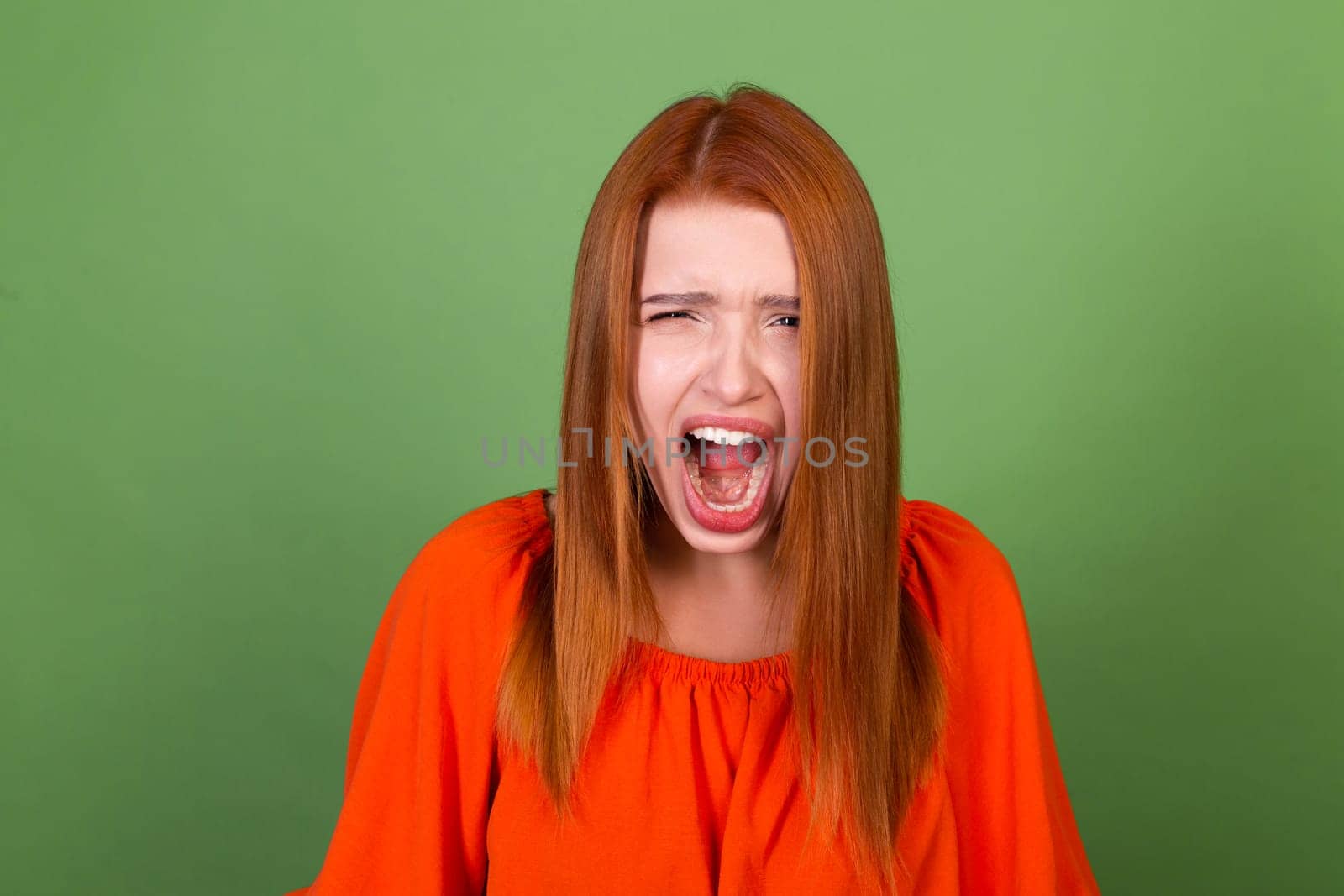 Young red hair woman in casual orange blouse on green background sad angry disappointed screaming by kroshka_nastya
