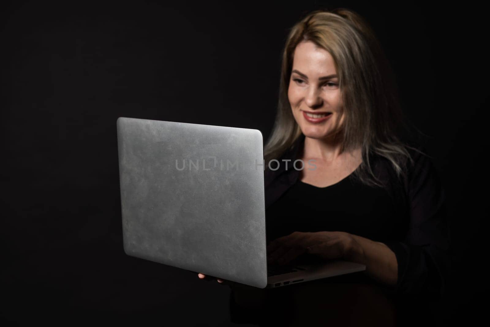 woman with laptop on black background.