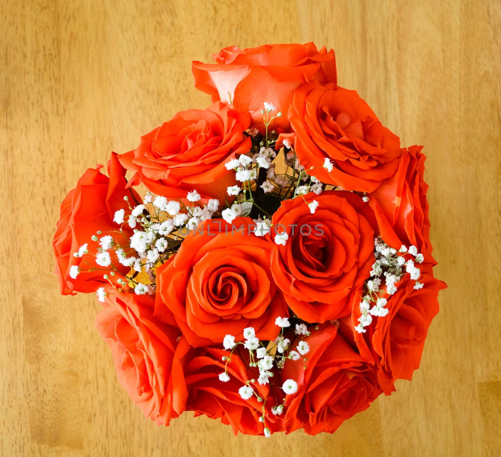Beautiful bouquet of red roses on a wooden table.