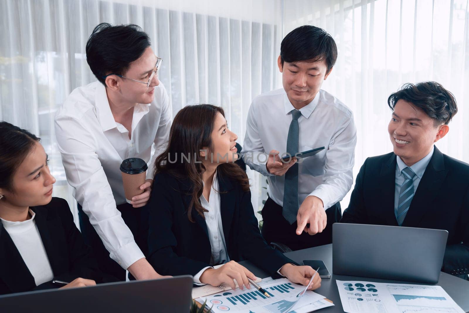 Harmony in office concept as business people analyzing dashboard paper together in workplace. Young colleagues give ideas at manager desk for discussion or strategy planning about project.