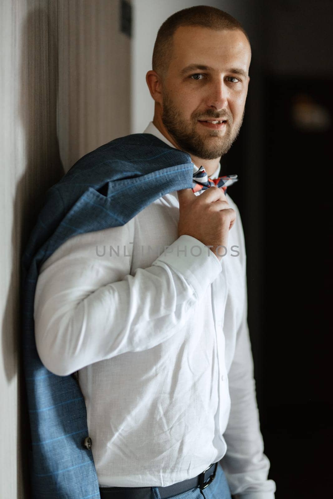 portrait of smiling groom with beard in blue color suit