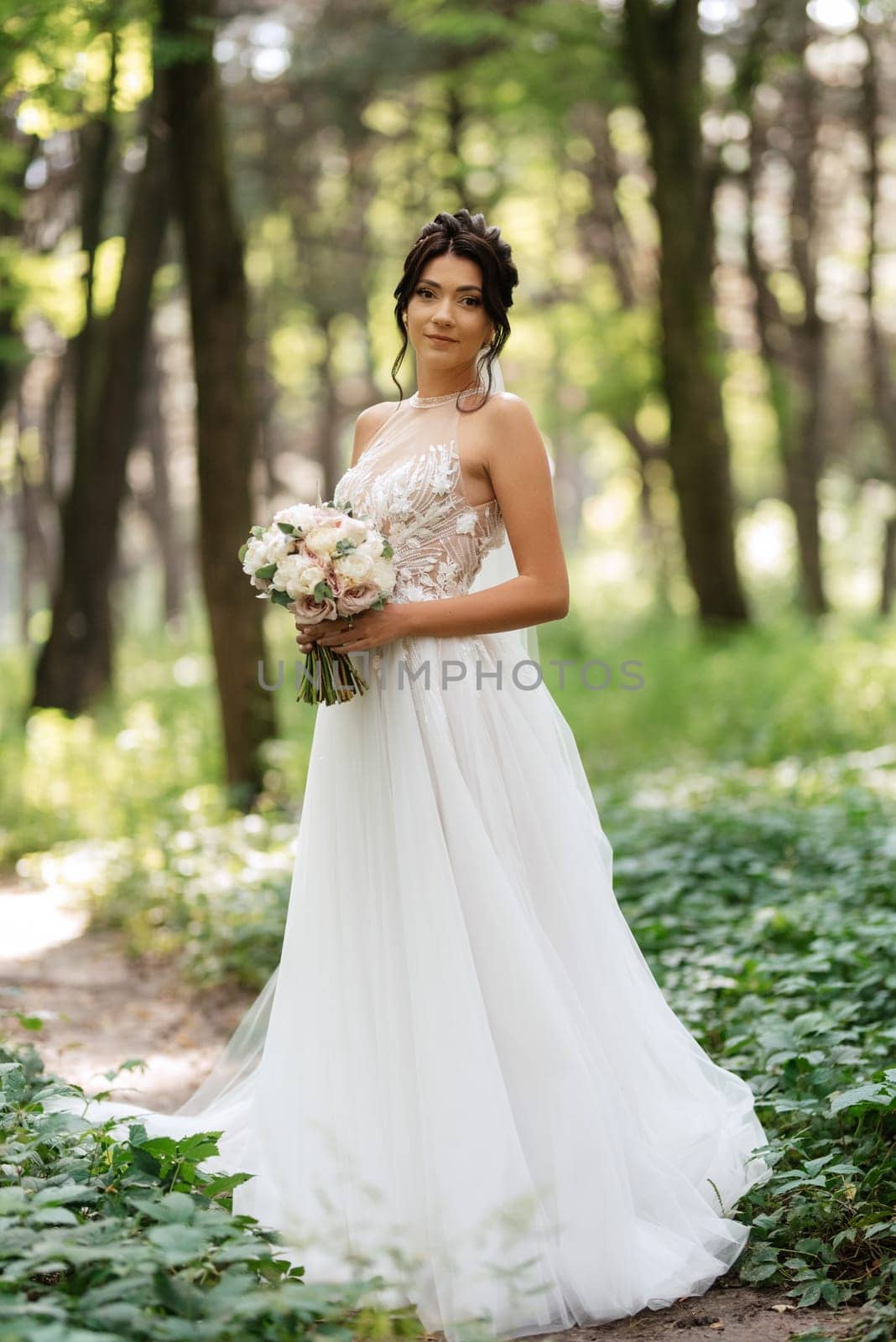 portrait of an elegant bride girl on a path in a deciduous forest with a bouquet by Andreua