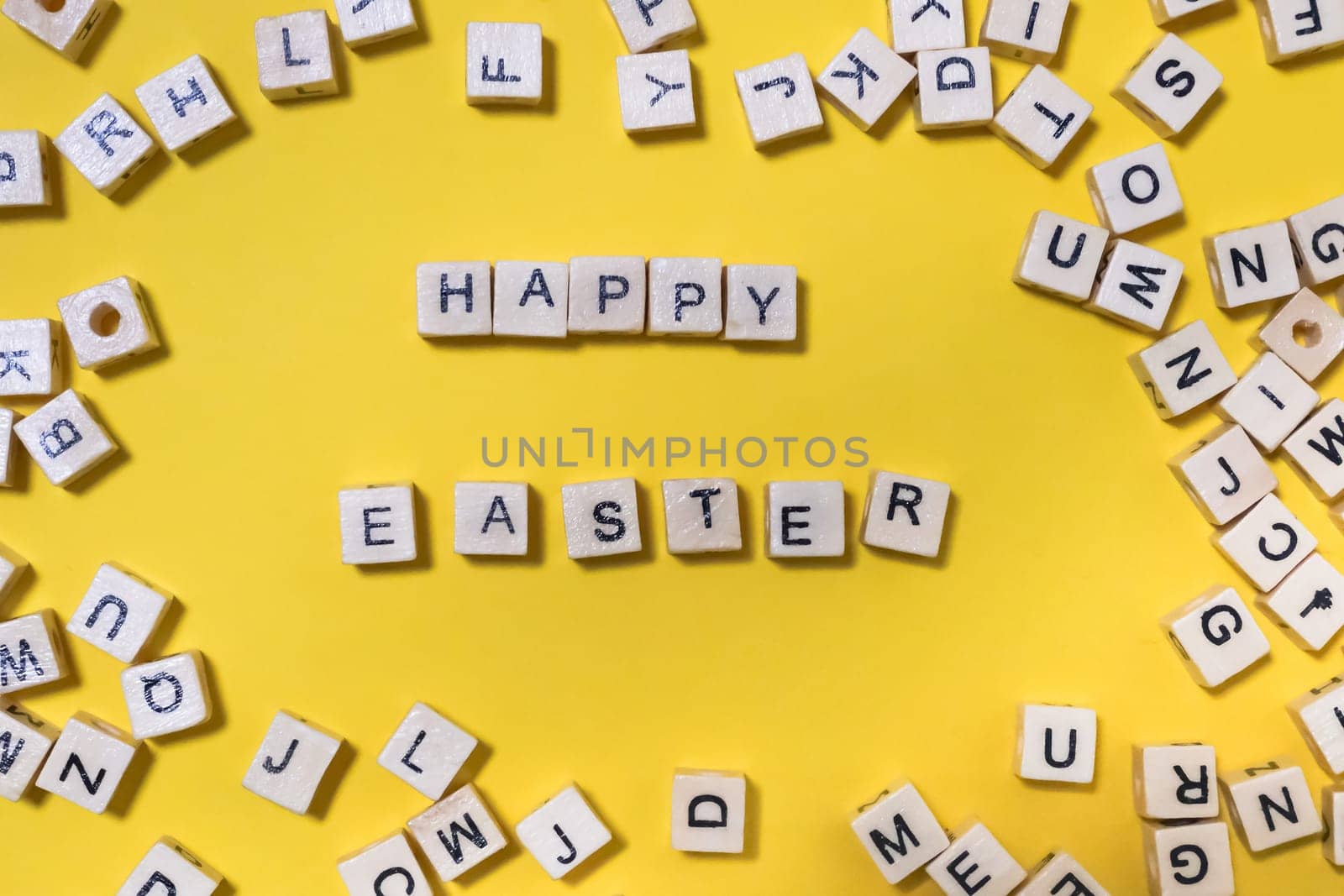  inscription on wooden cubes happy easter on yellow background. creative festive background with scattered letters