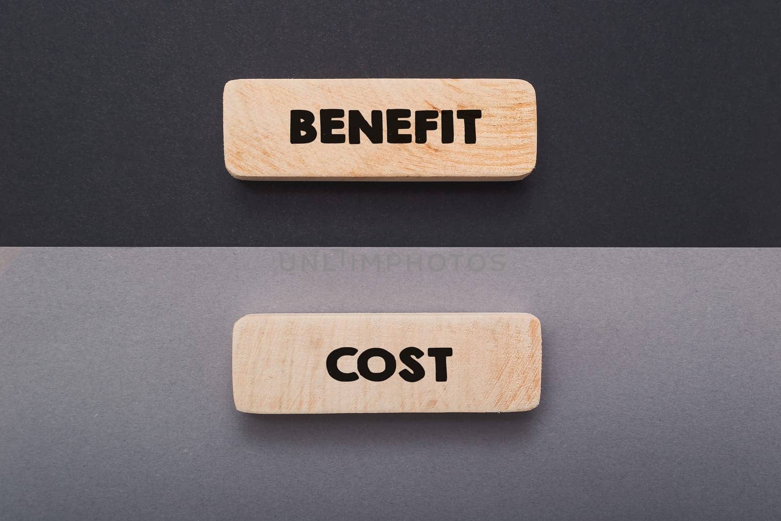 Small wooden tablets with words Benefit and Costs on black and grey background upper view. Traditional advantages and highlights of business