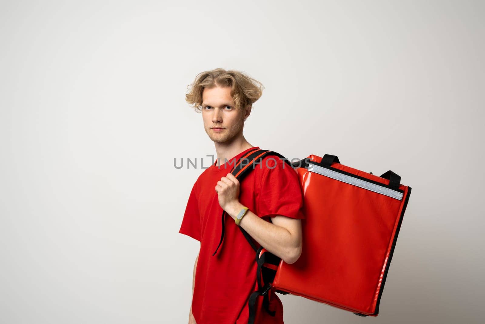 Courier delivers groceries home. Delivery man in red uniform with a thermal backpack isolated on a white background. Fast home delivery. Online order. by vovsht