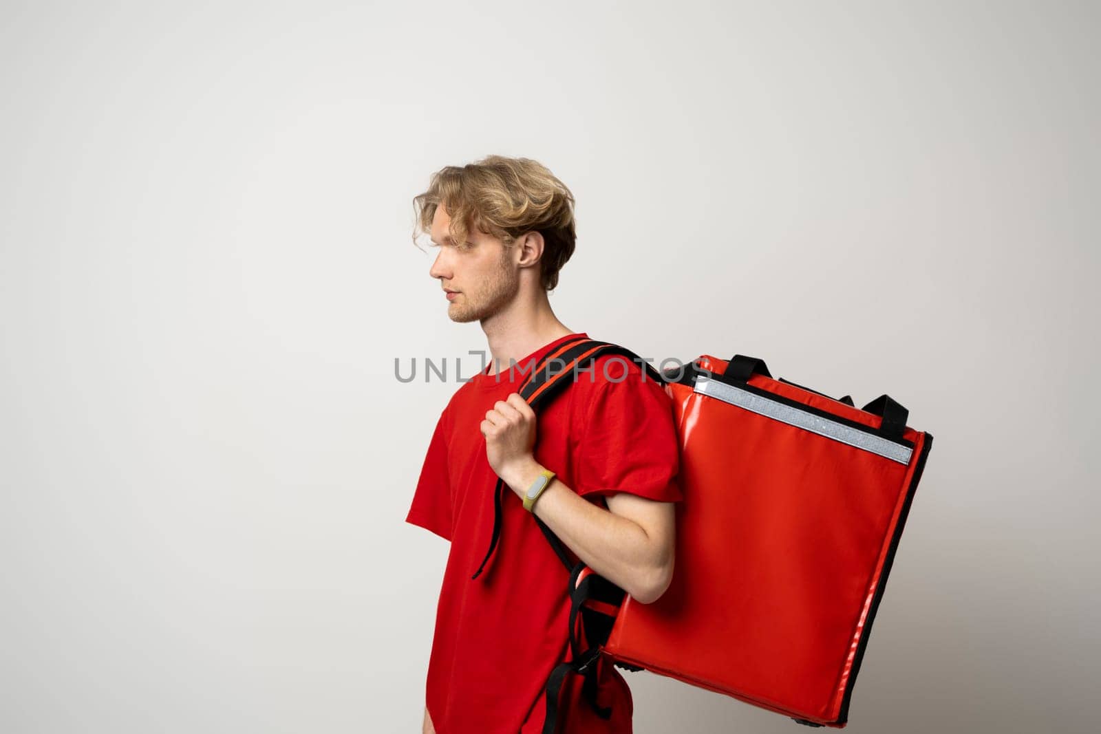 Delivery man in red uniform with thermal backpack for food. Takeaway food delivery. Man delivering online food orders to customers with red thermal bag, grocery deliver