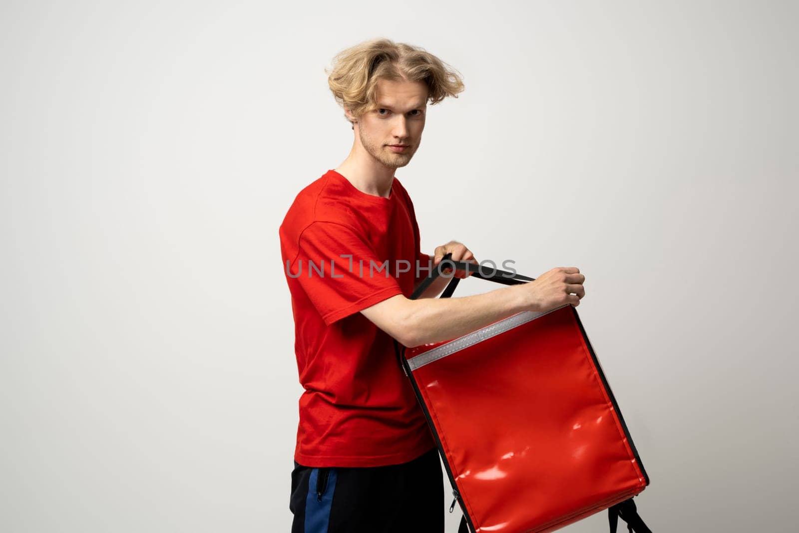 Young courier with thermo bag on white background. Food delivery service. by vovsht