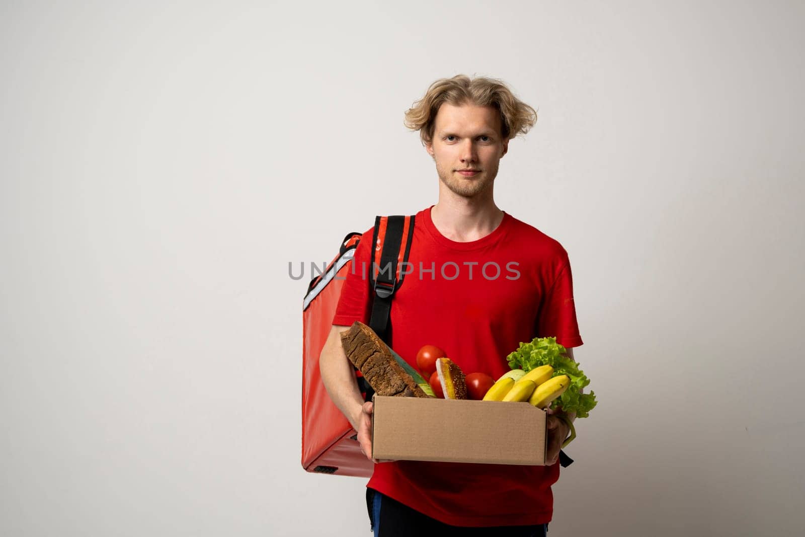 Handsome delivery man carrying package box of grocery food and drink from store. Isolated on white studio Background. Copy Space. Delivery Concept