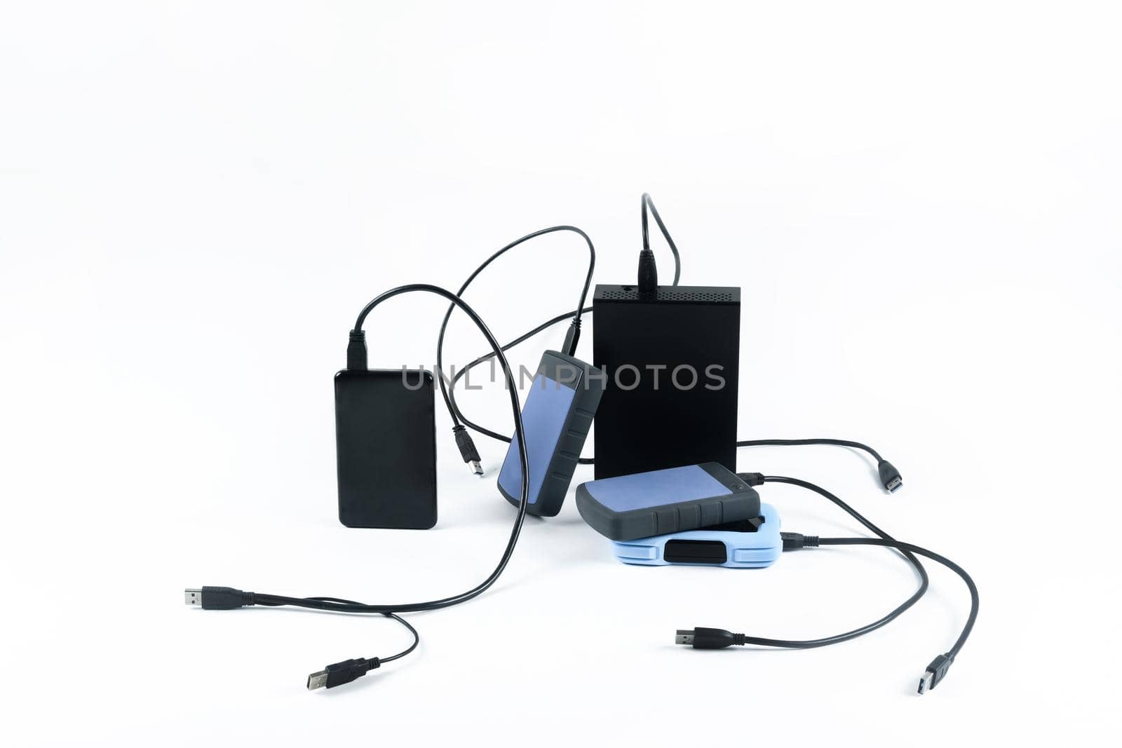 many external hard drives with wires lie on a white background. Hard drives on isolate